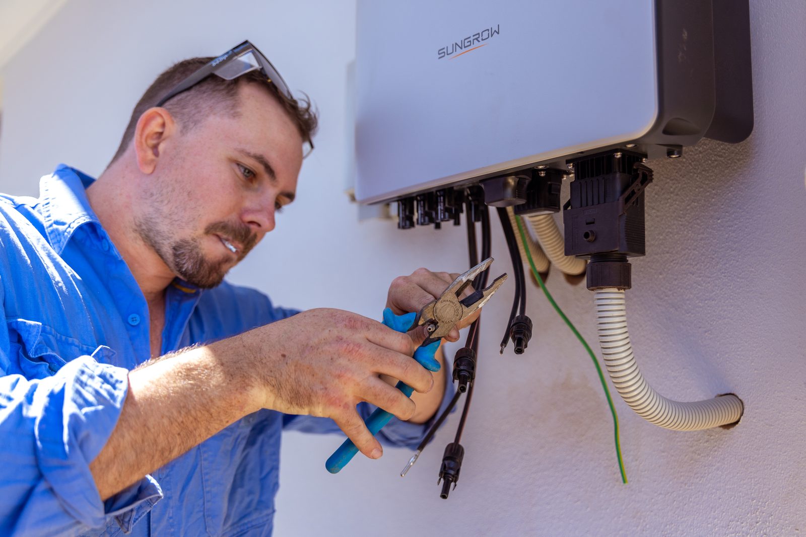 An electrician wiring an inverter on site